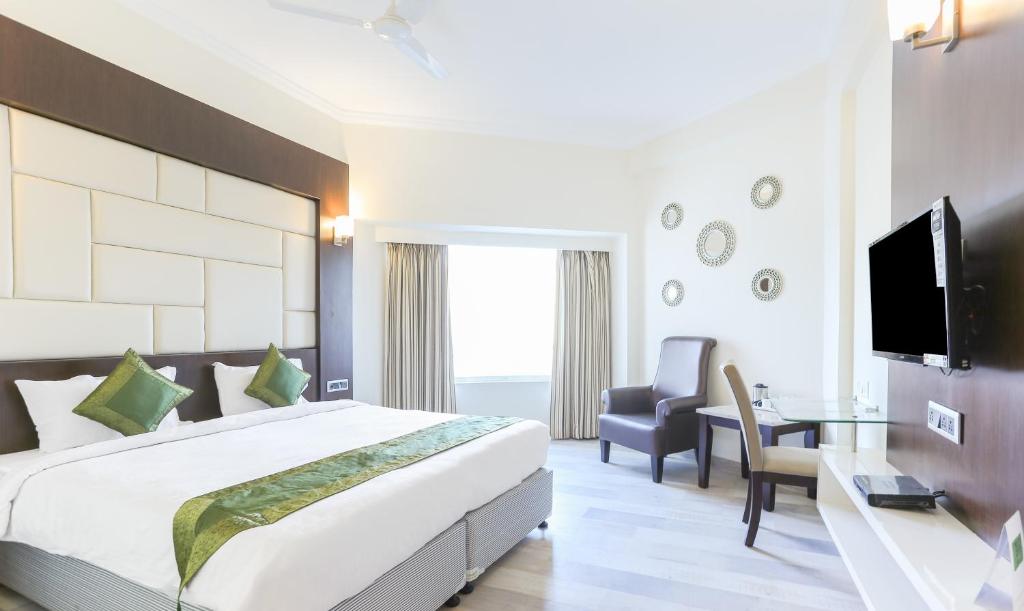 a hotel room with a bed and a desk and a tv at Treebo Trend Wood Bridge in Hyderabad
