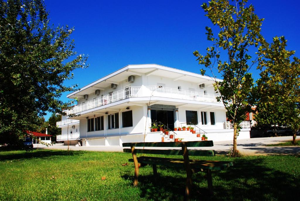 a white building with a bench in front of it at Hotel Kastri in Nea Mesangala