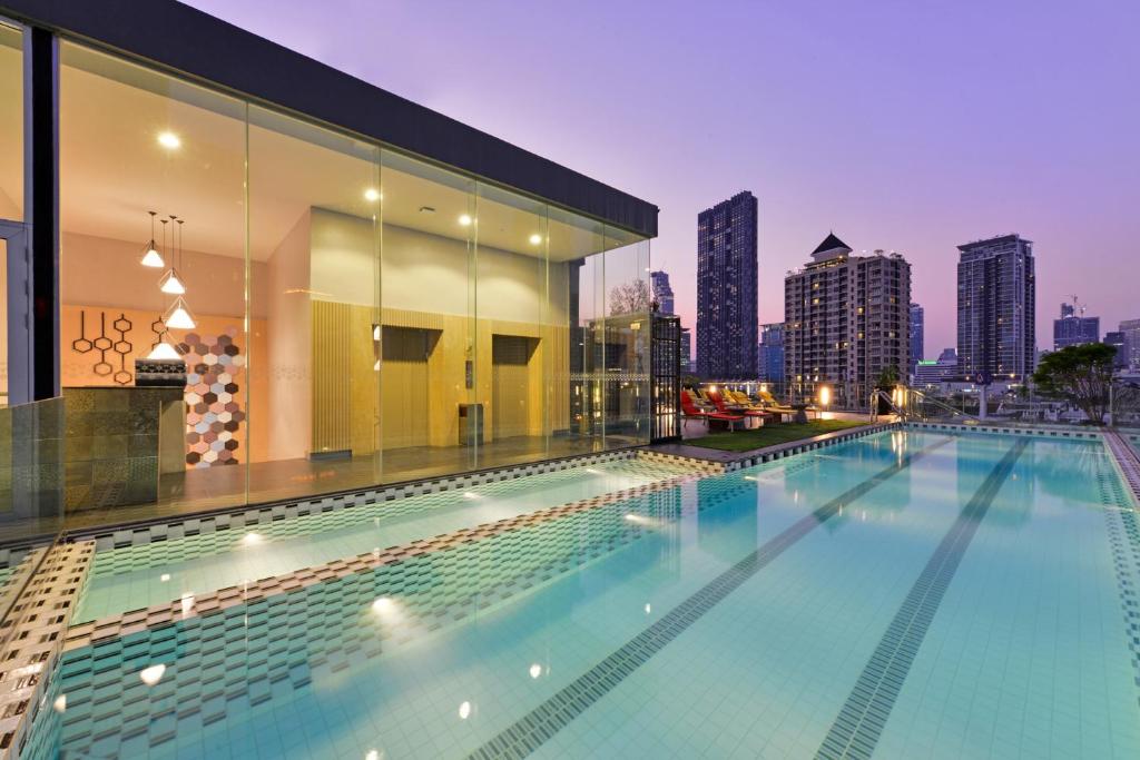 a swimming pool on the roof of a building with a city skyline at Le D'Tel Bangkok in Bangkok