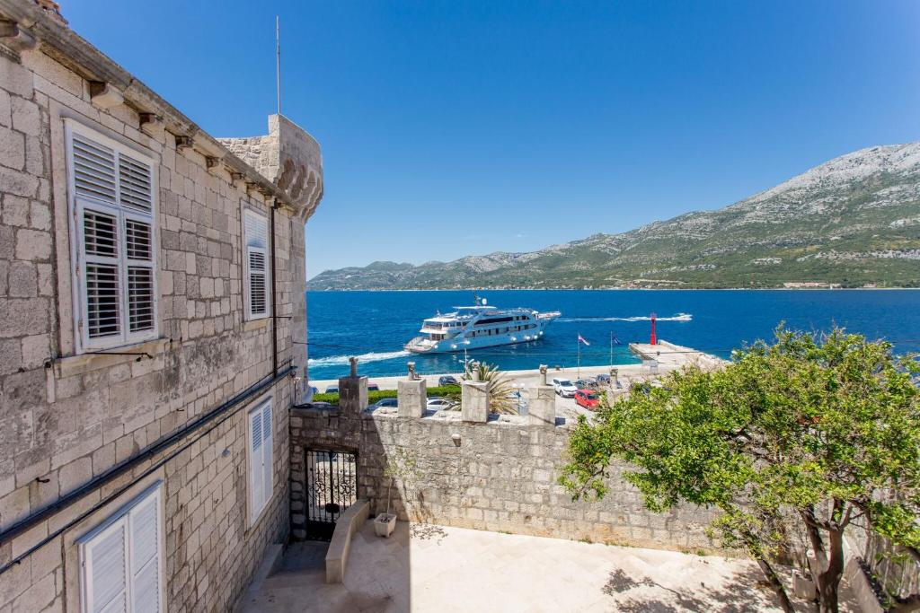 een gebouw met uitzicht op het water en een boot bij Korcula apartmanu Mili in Korčula