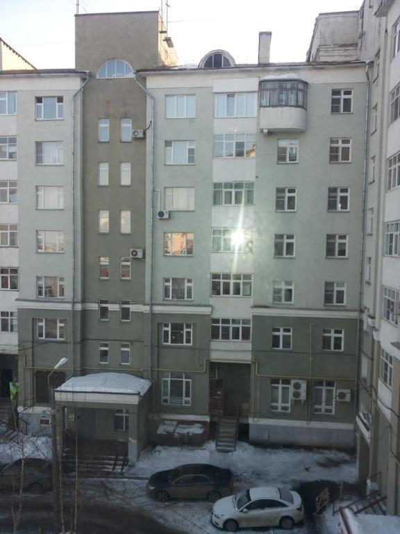 an apartment building with cars parked in front of it at Apartments on Kommunisticheskaya 25 in Saransk