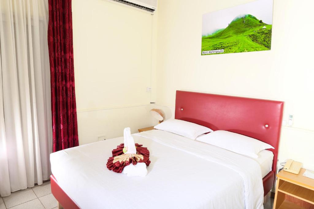 a bedroom with a large bed with a red headboard at Hotel Mansel in Yaoundé