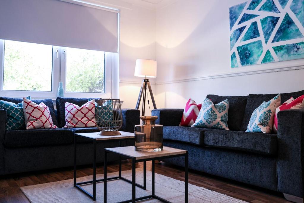 a living room with two couches and a table at Meadowburn View in Wishaw