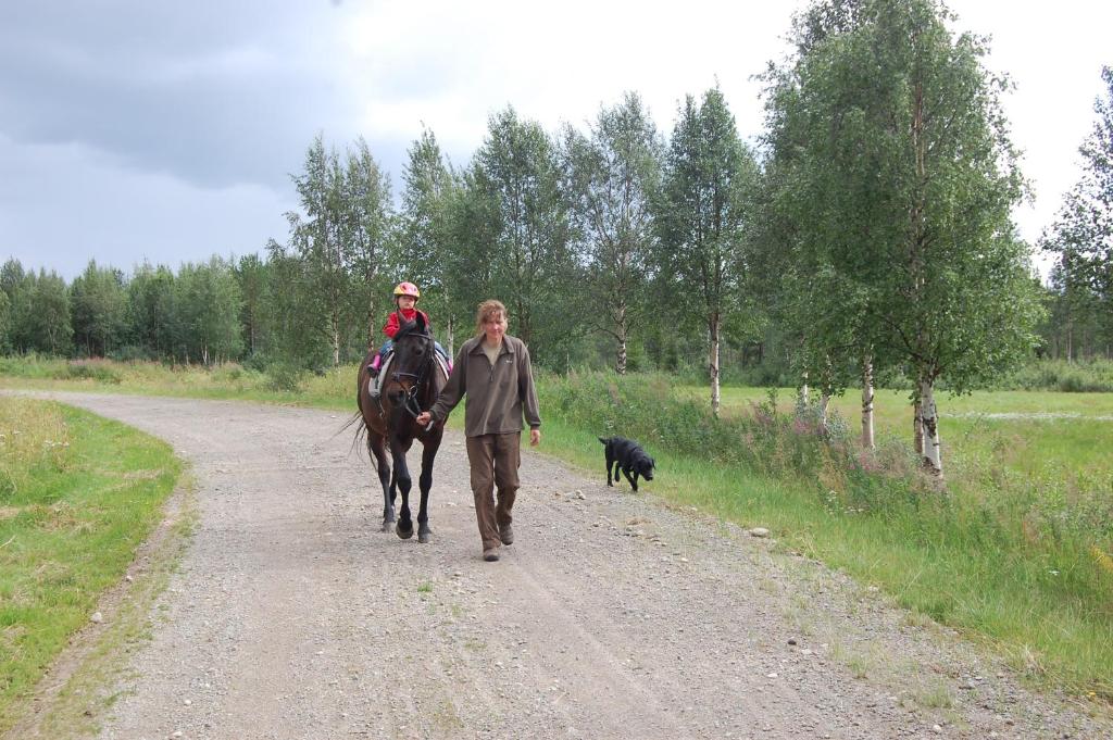 a man and a man walking a horse down a dirt road at Aha Lodge in Sorsele