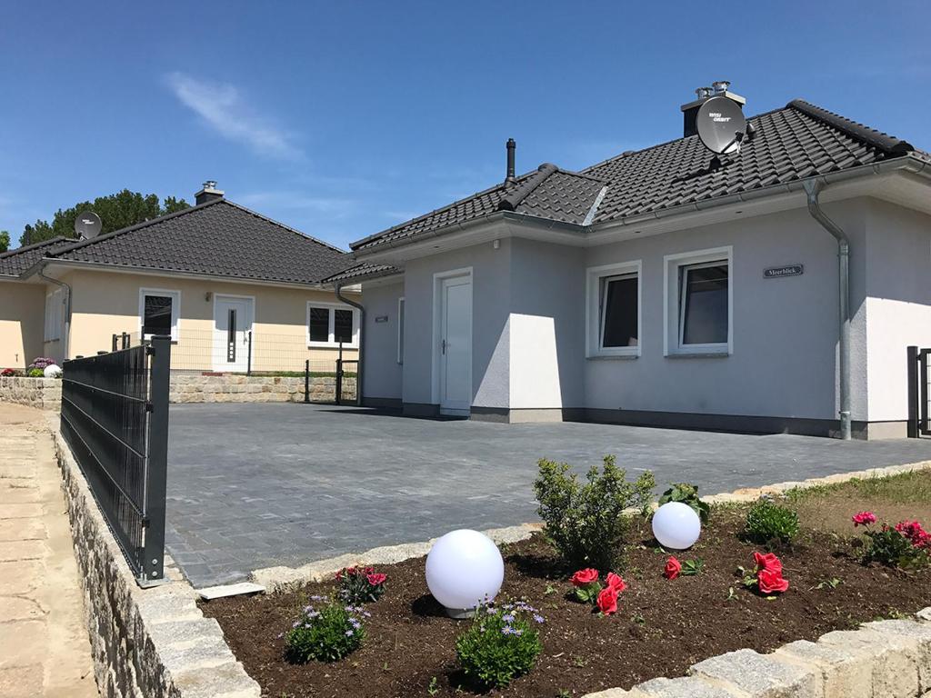 ein Haus mit Auffahrt und Blumen im Hof in der Unterkunft Ferienwohnungen am Hafen in Stahlbrode