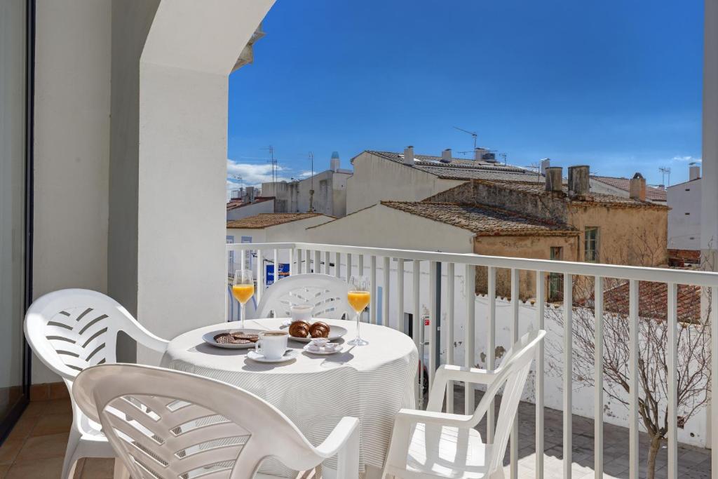 une table blanche avec une assiette de nourriture sur un balcon dans l'établissement Empordanet 1A, à Palafrugell