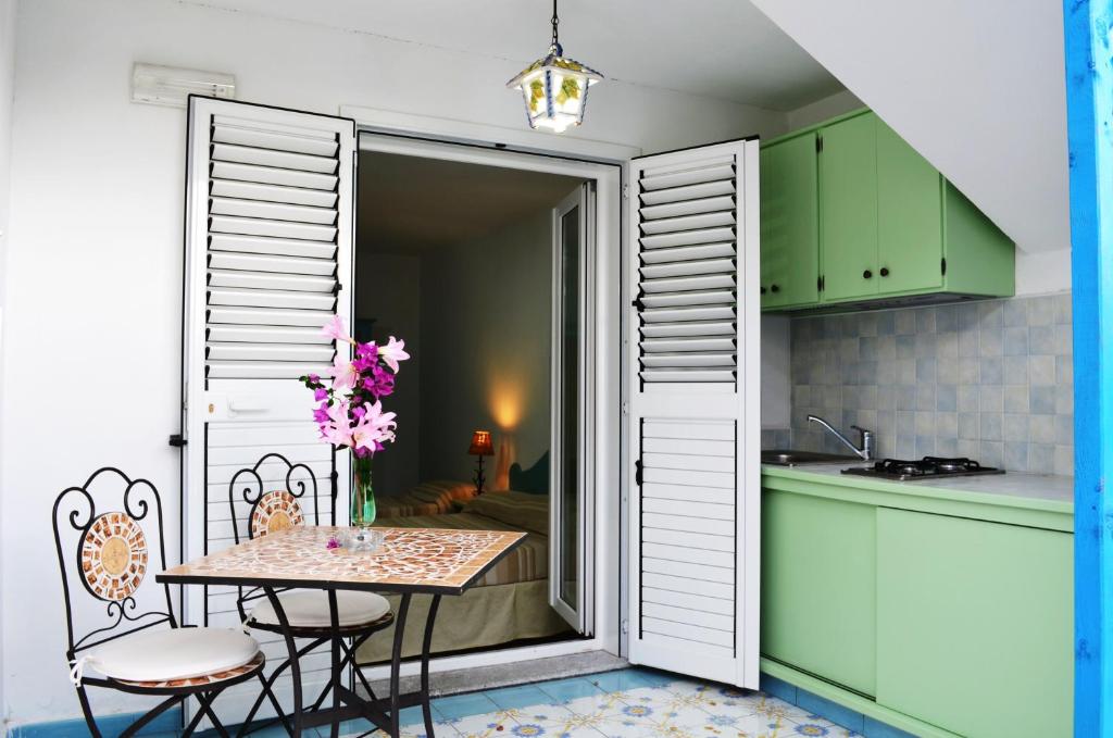 una cucina con tavolo e sedie e una cucina con armadi verdi di Villa La Gioiosa a Maratea