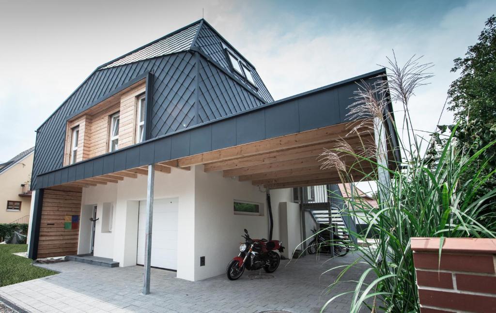 uma casa com um telhado preto e uma moto estacionada em frente em Studios + em Graz