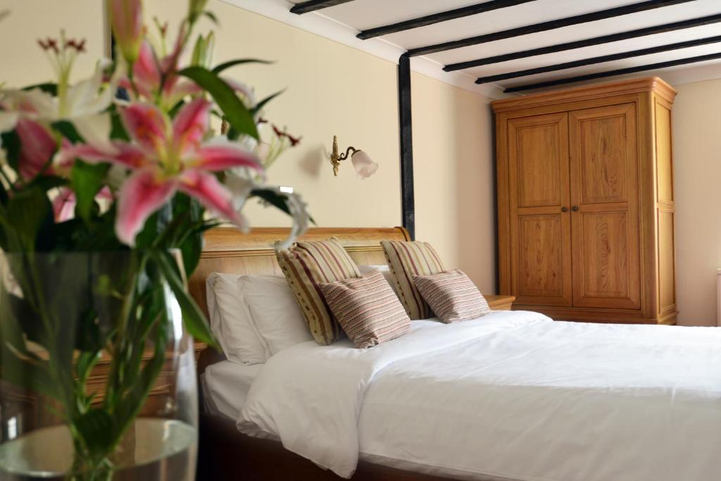 Un dormitorio con una cama con un jarrón de flores en The Brickwall Hotel en Sedlescombe
