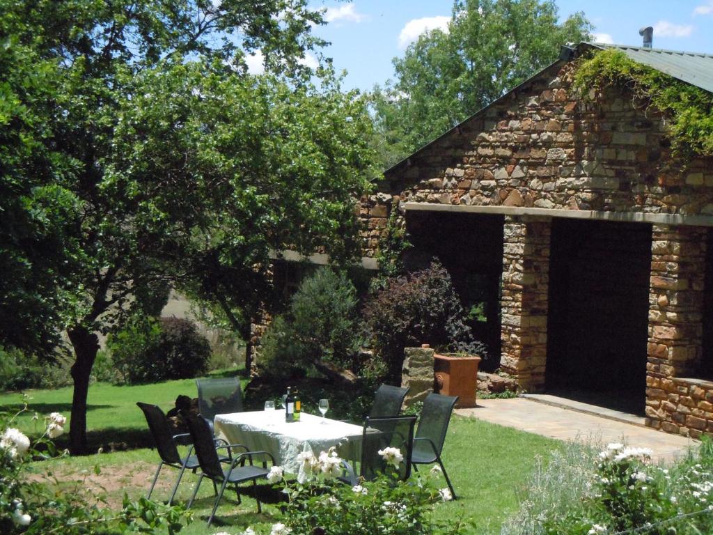 a table and chairs in front of a stone building at Bethel Lodge in Clarens