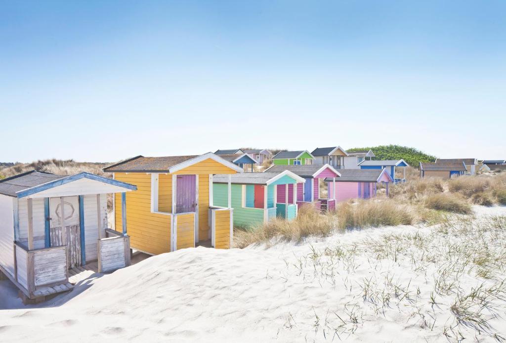 una fila de coloridas casas de playa en la playa en Skanörs Gästgifvaregård, en Skanör med Falsterbo