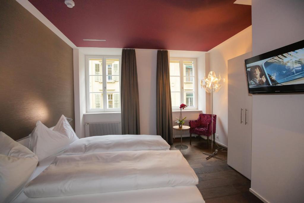 a hotel room with two beds and a flat screen tv at Boutique Hotel - Restaurant Orchidee in Burgdorf