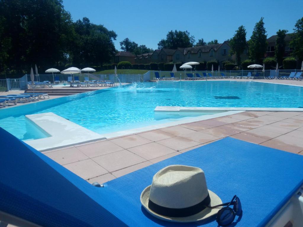 un sombrero y gafas de sol sentados en una mesa en una piscina en Résidence Lac Mondésir, en Monflanquin