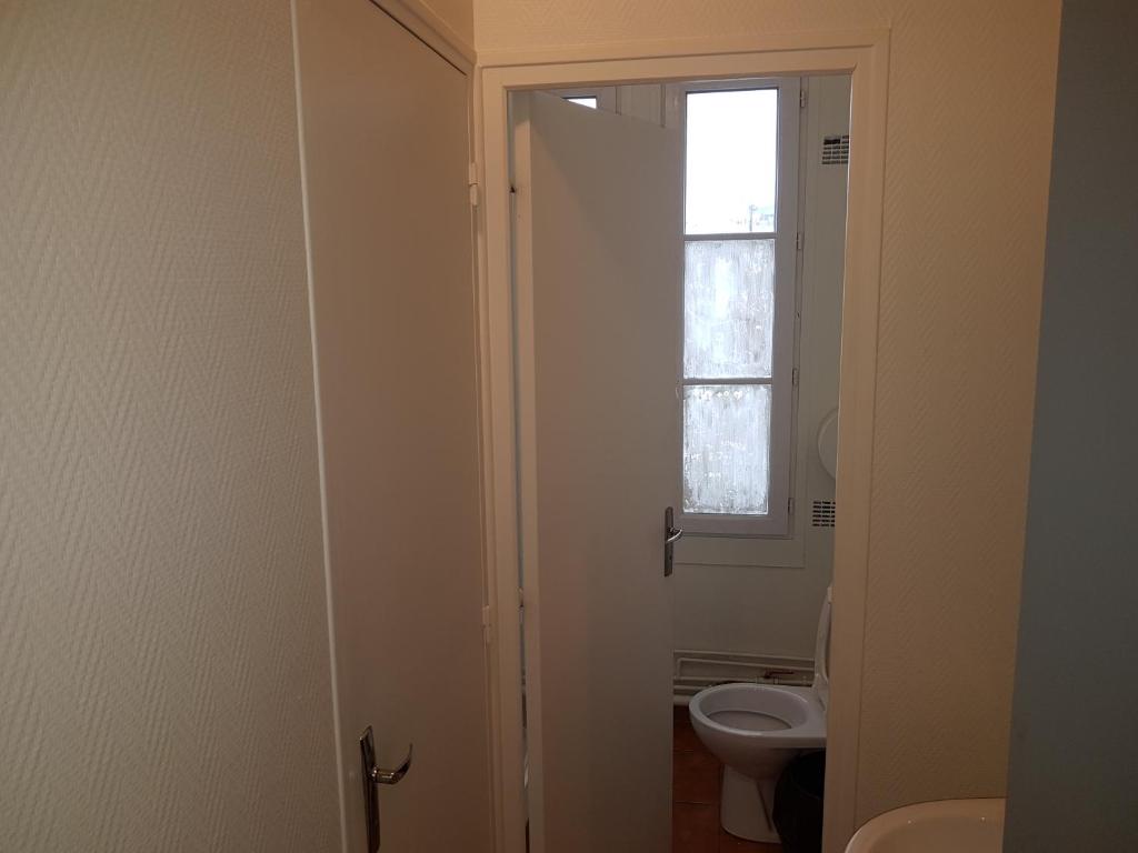a bathroom with a toilet and a window at Au Royal Mad in Paris