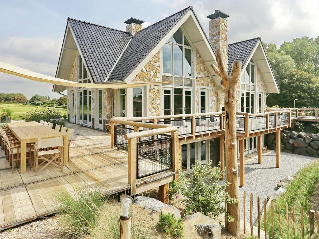 a house with a large deck with a table and chairs at Holiday Home with bubble bath in Noordwijk in Noordwijk