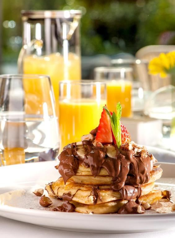 a stack of pancakes with chocolate and strawberries on a plate at Somewhere Vouliagmeni in Athens