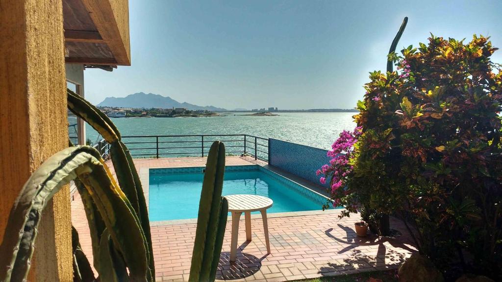 uma varanda com uma piscina junto à água em Hospedagem Sol e Mar em Vila Velha