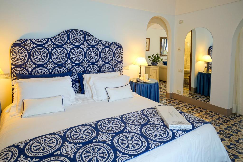 a bedroom with a large bed with a blue and white bedspread at Hotel Villa Cimbrone in Ravello