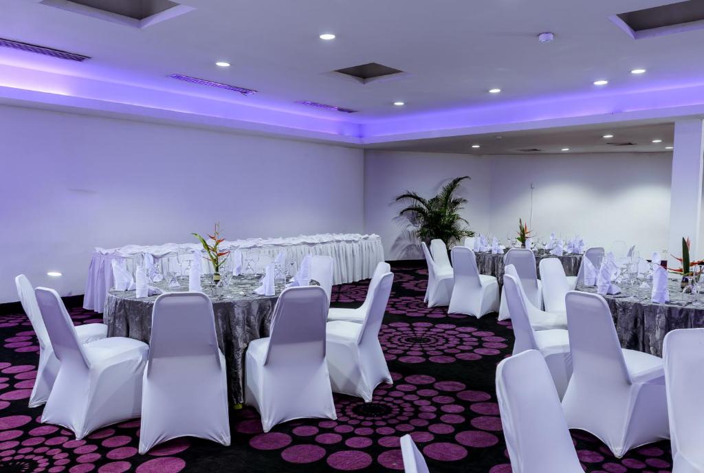 a conference room with white chairs and tables and a screen at Riande Aeropuerto Hotel Casino in Tocumen