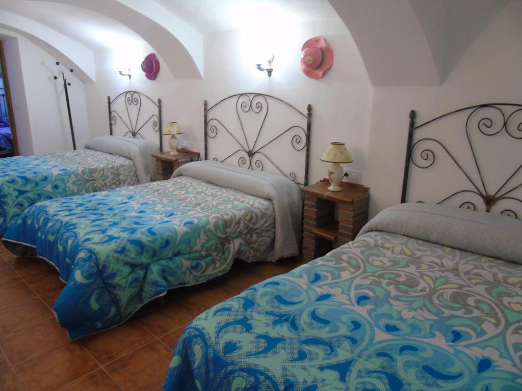 a bedroom with two beds with blue and green sheets at Cueva El Jaraiz in Guadix