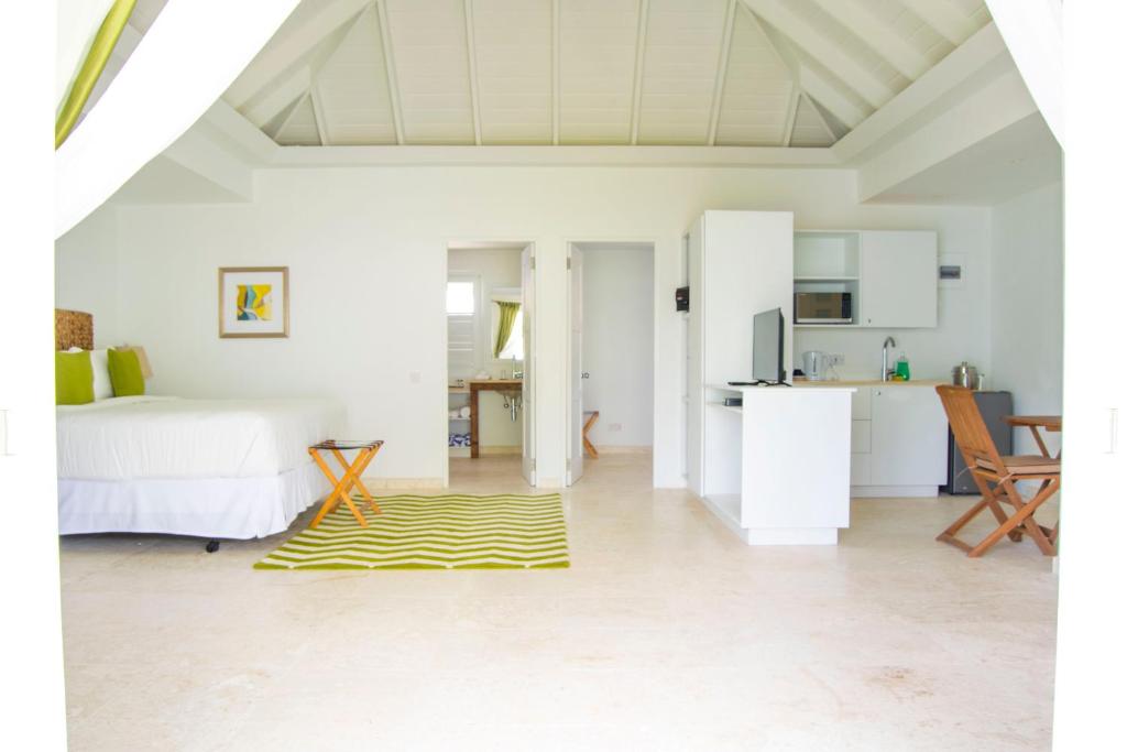 a white room with a bed and a yellow rug at Bequia Plantation Hotel in Bequia