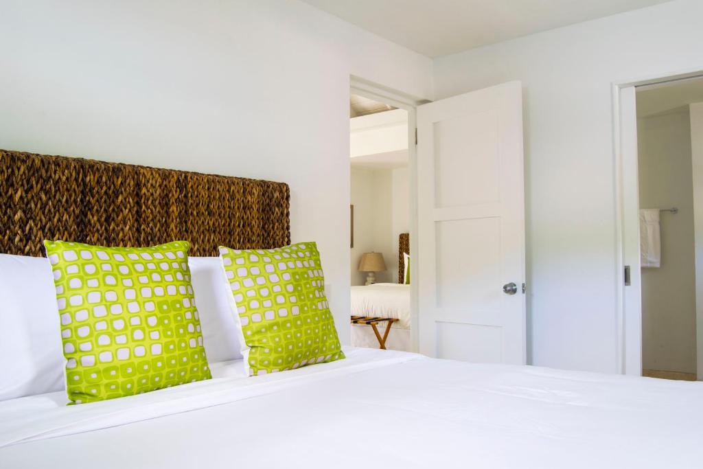 a bedroom with a white bed with green pillows at Bequia Plantation Hotel in Bequia