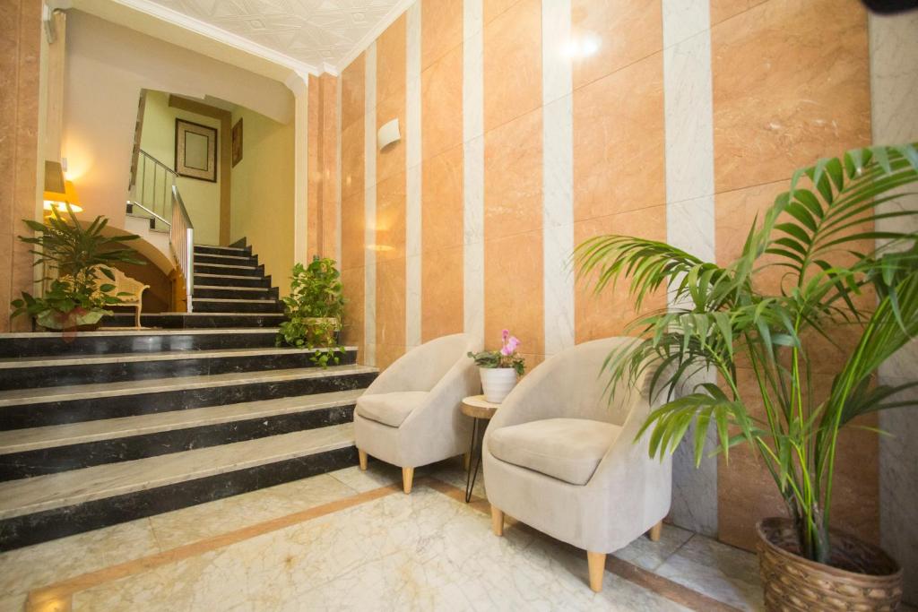 a lobby with two chairs and stairs with plants at Pensión Belmonte II in Benicarló