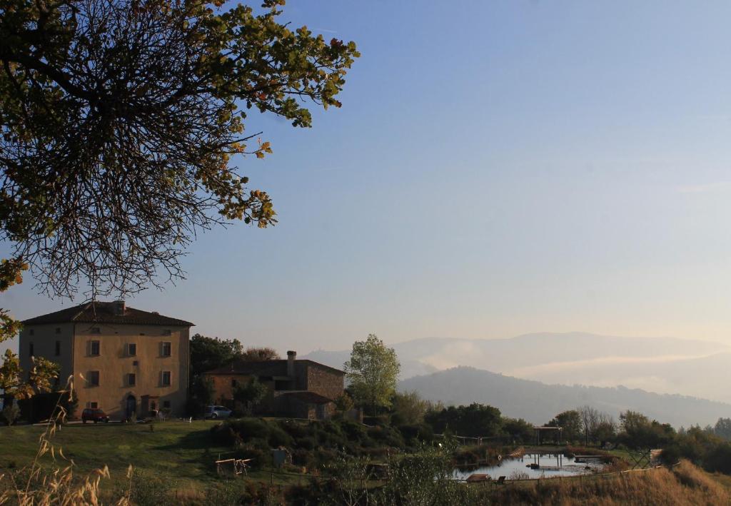 una casa en una colina con un lago y montañas en el fondo en Fattoria San Paolo Agriturismo, en Montecastelli