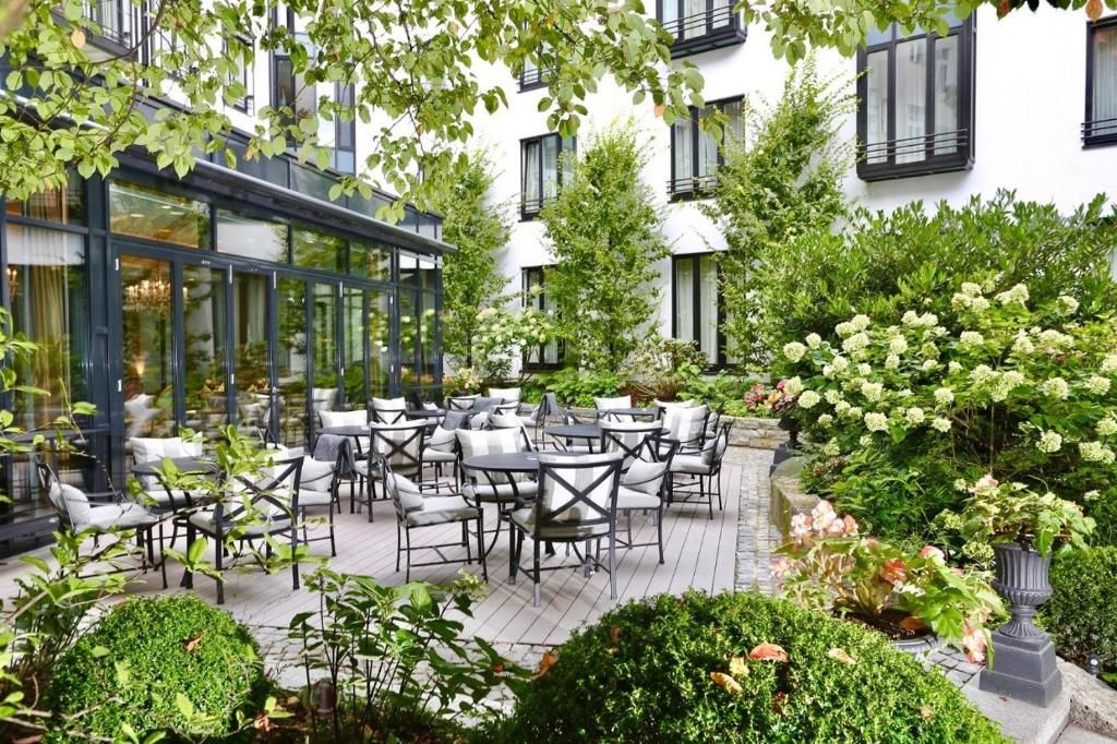 un patio al aire libre con mesas, sillas y flores en Hotel München Palace, en Múnich