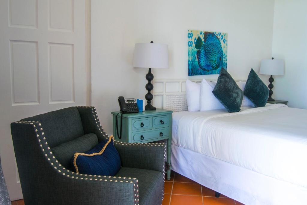 a bedroom with a bed and a chair and a night stand at Bequia Plantation Hotel in Bequia