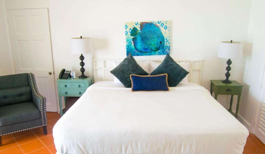 a bedroom with a white bed and a chair at Bequia Plantation Hotel in Bequia