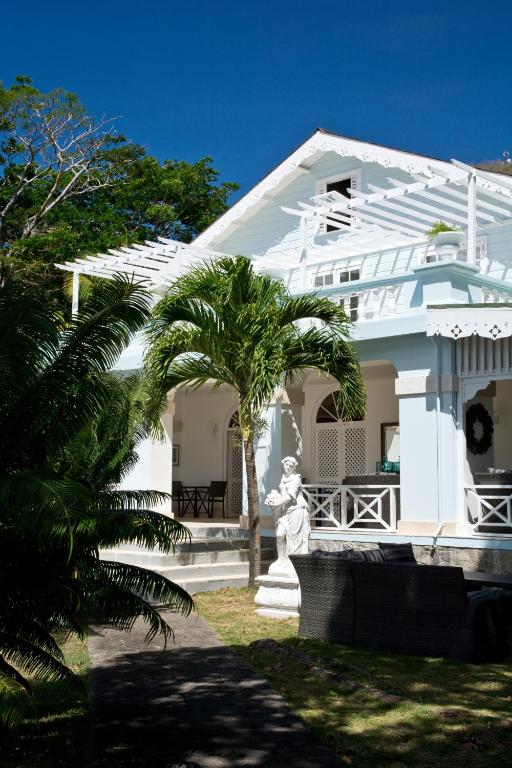 a white house with a statue in front of it at Bequia Plantation Hotel in Bequia