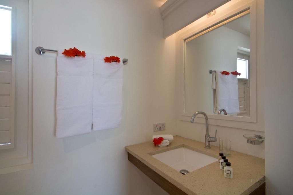 a white bathroom with a sink and a mirror at Bequia Plantation Hotel in Bequia