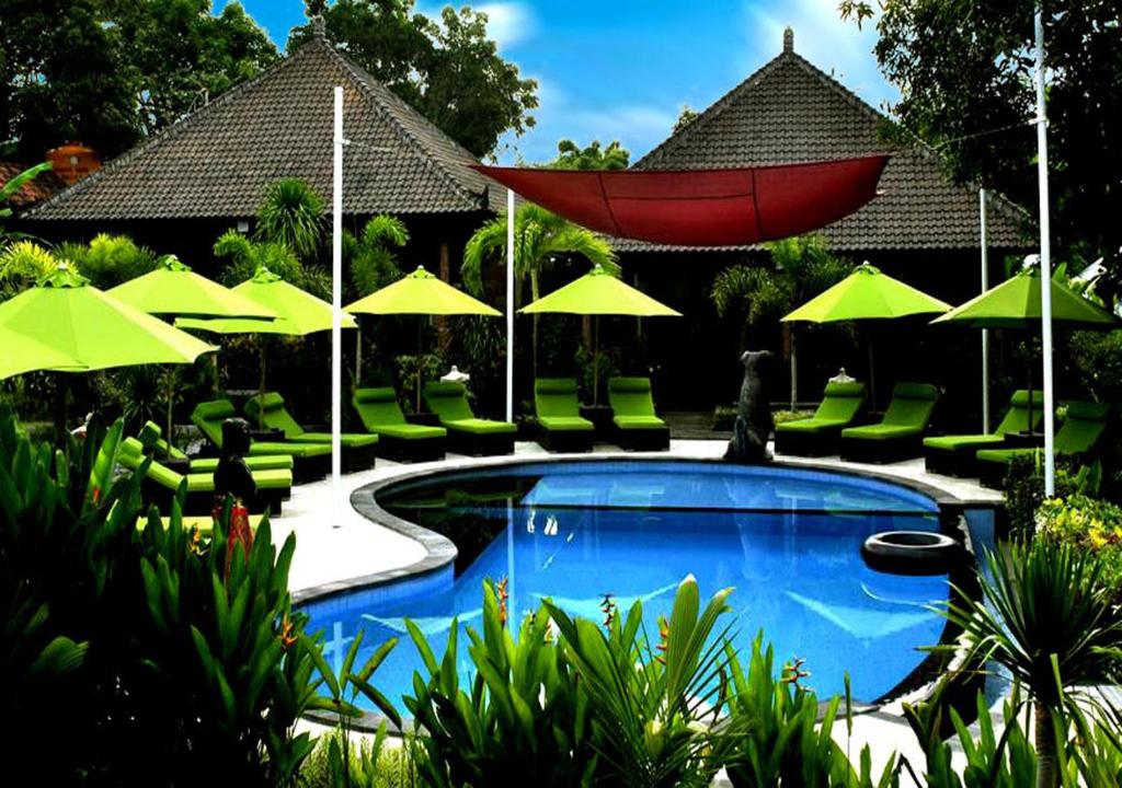 a swimming pool with green chairs and umbrellas at Damara Lembongan in Nusa Lembongan