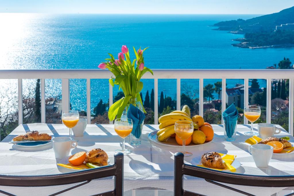 uma mesa com pratos de comida e vista para o oceano em Summer Experience Apartment em Mlini