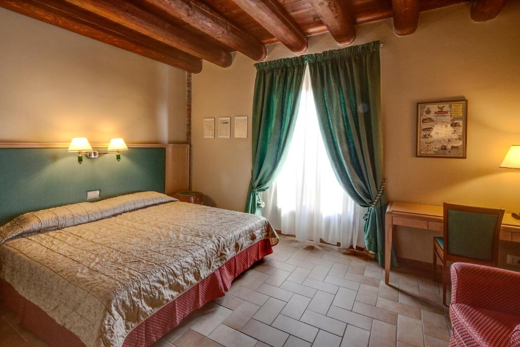een slaapkamer met een bed en een raam met groene gordijnen bij Hotel Residence Diamantina in Ferrara