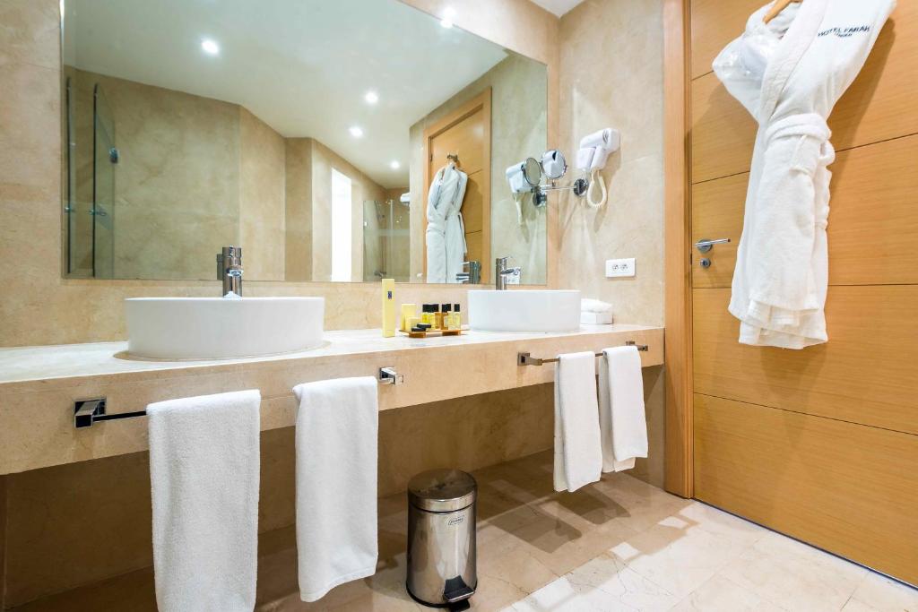 a bathroom with two sinks and a mirror with towels at Hotel Farah Tanger in Tangier