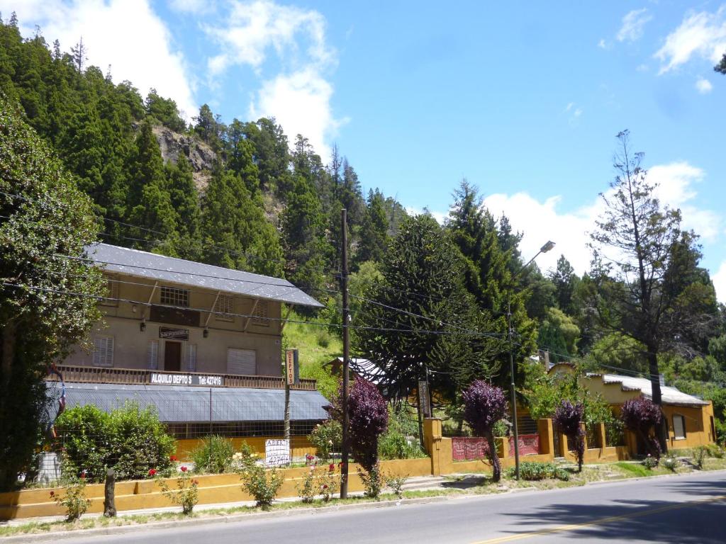 a building on the side of a road with trees at Sacromonte Apart in San Martín de los Andes