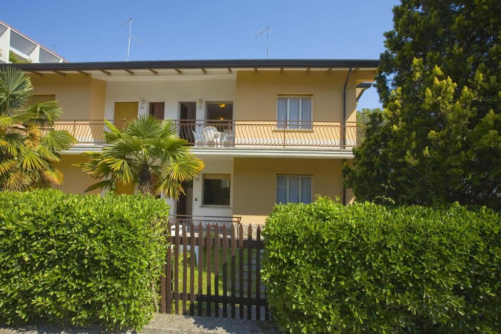 een geel huis met een balkon en struiken bij Angela in Bibione