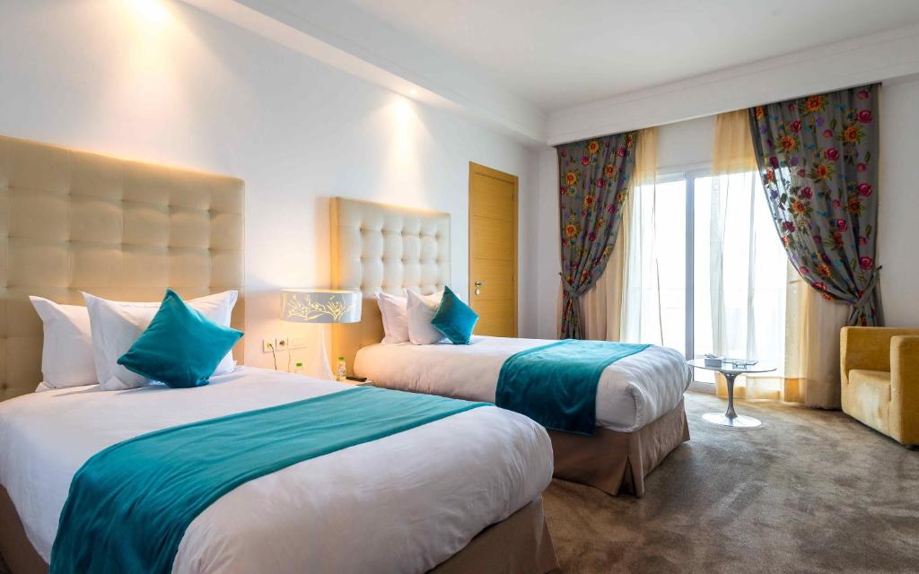 a hotel room with two beds and a window at Hotel Farah Tanger in Tangier