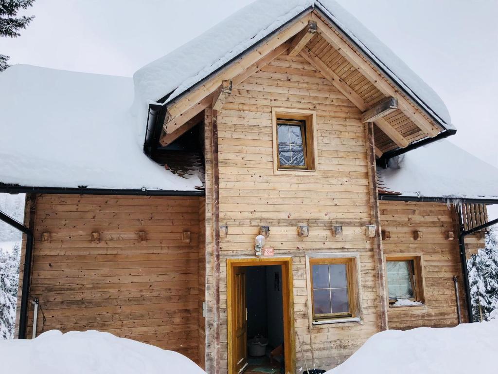Cabaña de madera con nieve en el techo en Apartmaji Zlata Lisička en Cerkno