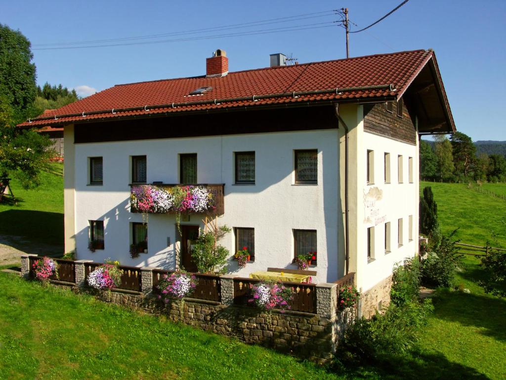 uma casa branca com flores ao lado dela em Ferienwohnungen am Arber em Lohberg