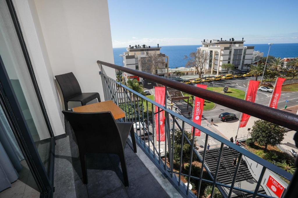 een balkon met een tafel en stoelen en de oceaan bij Forum Madeira Ocean View I in Funchal