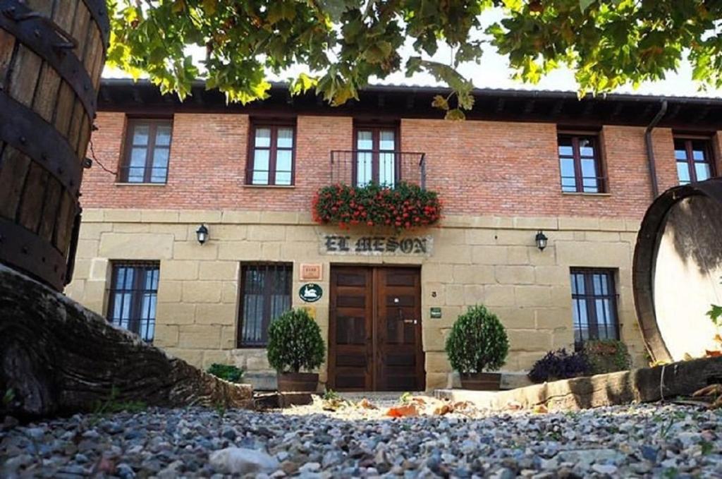 un edificio in mattoni con una porta e fiori di Casa Rural El Meson a Briones