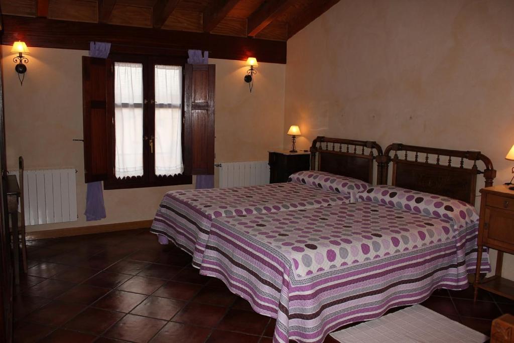 a bedroom with two beds and two windows at Casa Rural El Meson in Briones