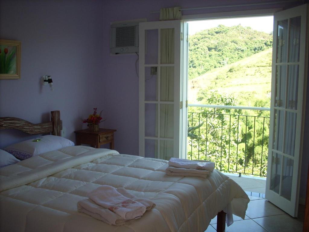 a bedroom with a bed and a large window at Pousada D'amoras in Conservatória