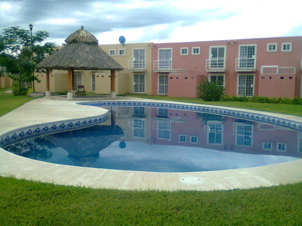 a swimming pool with a gazebo and a building at Casa Flores in Acapulco