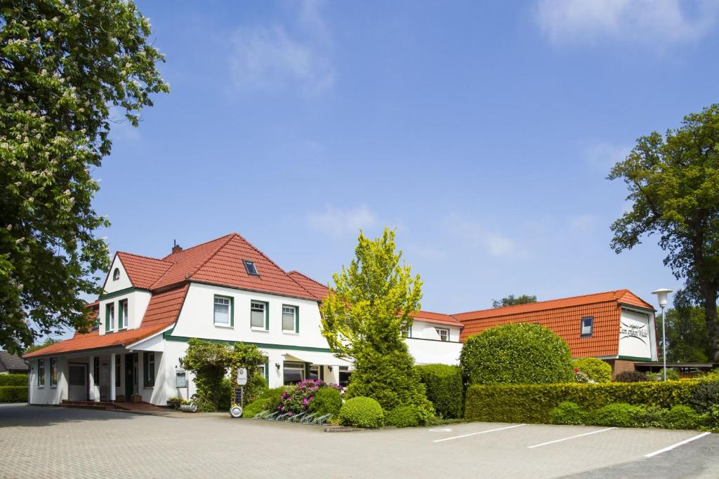 uma casa branca com um telhado vermelho em Landgasthof "Zum grünen Walde" em Nordholz