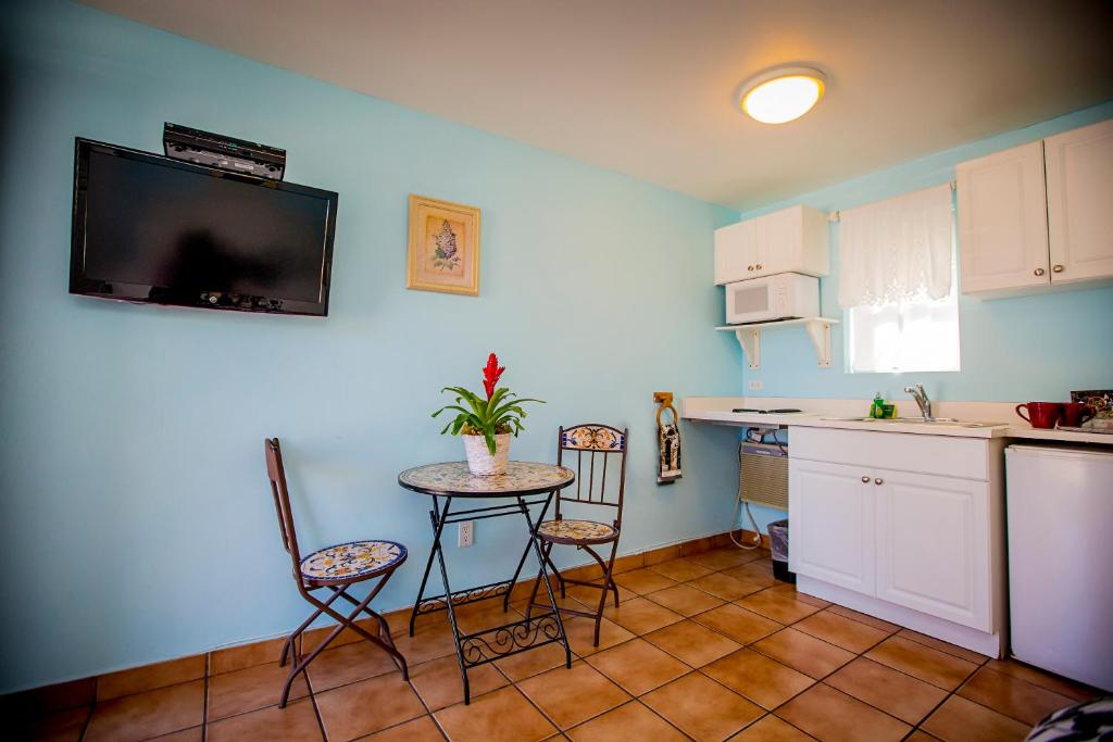 a kitchen with a table and chairs and a tv on the wall at Leucadia Beach Inn in Encinitas