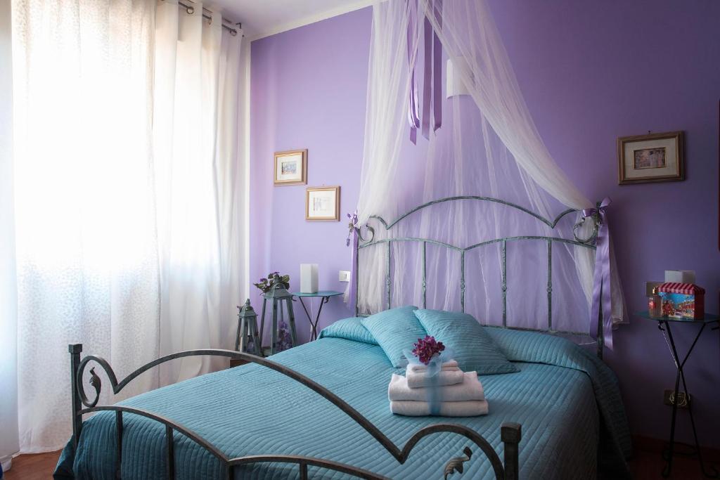 Albergo La Bussola في أبادييا سان سالفاتور: غرفة نوم أرجوانية مع سرير عليه مناشف